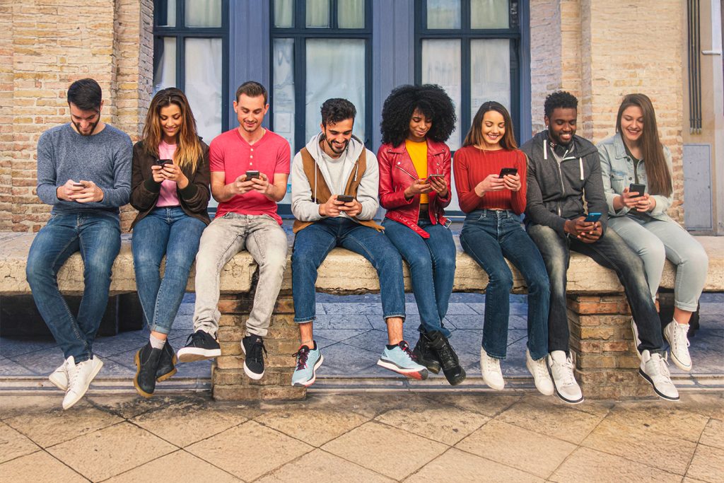 college studnet sitting on a bench sharing photos on their smartphones