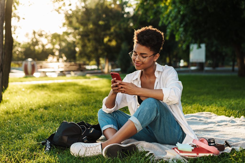 Woman looking at her phone in the sun at the park