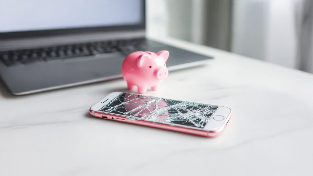 phone screen damaged with a piggy bank in the back
