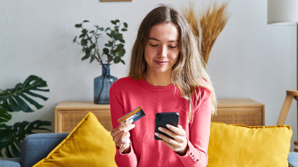 woman reading her credit card to make a purchase on her smartphone