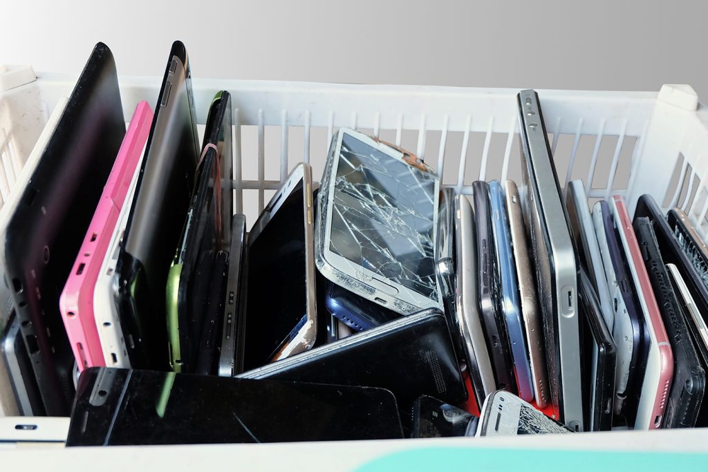 bin of old broken smartphones in a basket